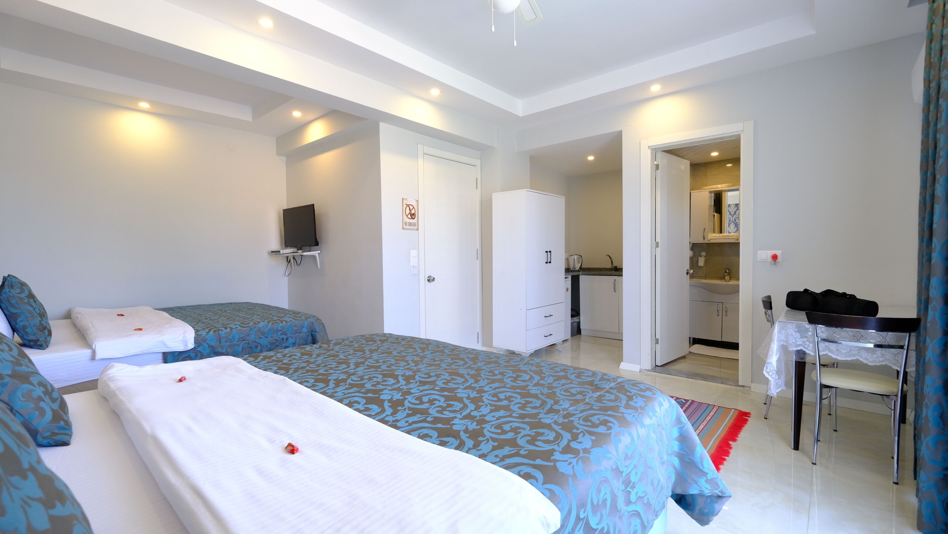 Habitación de hotel con dos camas, un armario, baño y un escritorio con silla.