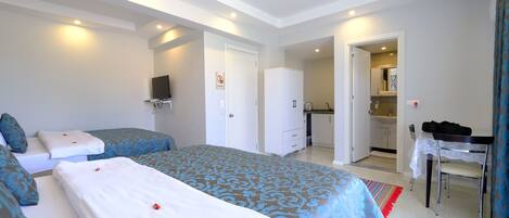 Habitación de hotel con dos camas, un armario, baño y un escritorio con silla.