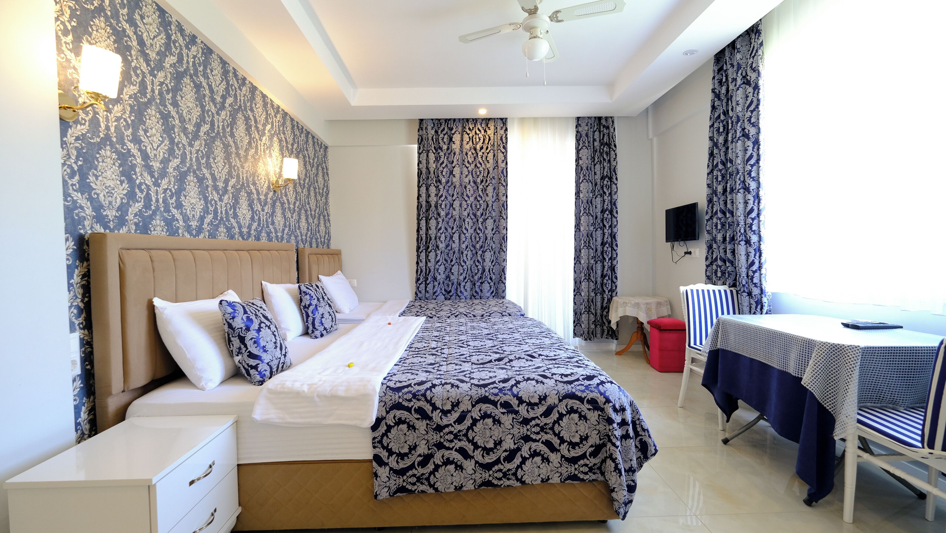 A neatly arranged bedroom with a bed, bedside tables, a desk, and a chair.