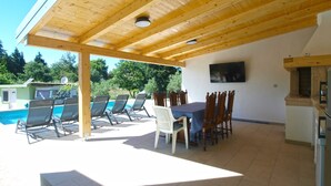 A covered outdoor area with a pool, lounge chairs, a dining table with chairs, and a TV mounted on the wall. - House 1548/15836 (Istria - Fažana), 3150m from the beach (Fažana)