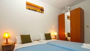 A hotel room with two beds, a wooden wardrobe, a painting on the wall, and bedside lamps. - House 1548/15836 (Istria - Fažana), 3150m from the beach (Fažana)