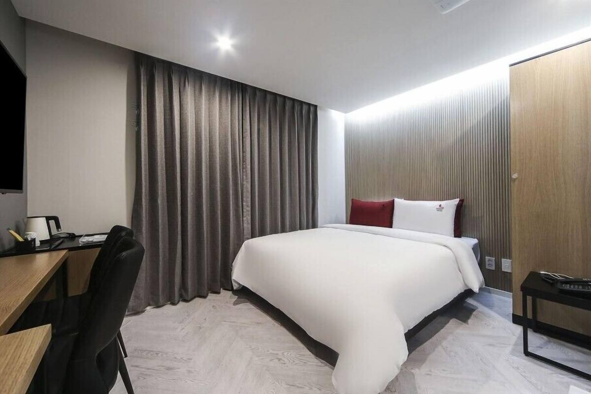 A modern hotel room with a large bed, a desk, and a TV.