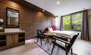 Una habitación de hotel moderna con una pared de madera, un ventanal con vistas, una cama, un escritorio y una silla.