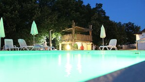 A swimming pool with lounge chairs and umbrellas, surrounded by trees and a wooden deck structure. - Apartment 1561/15973 (Istria - Žminj), 20000m from the beach (Žminj)