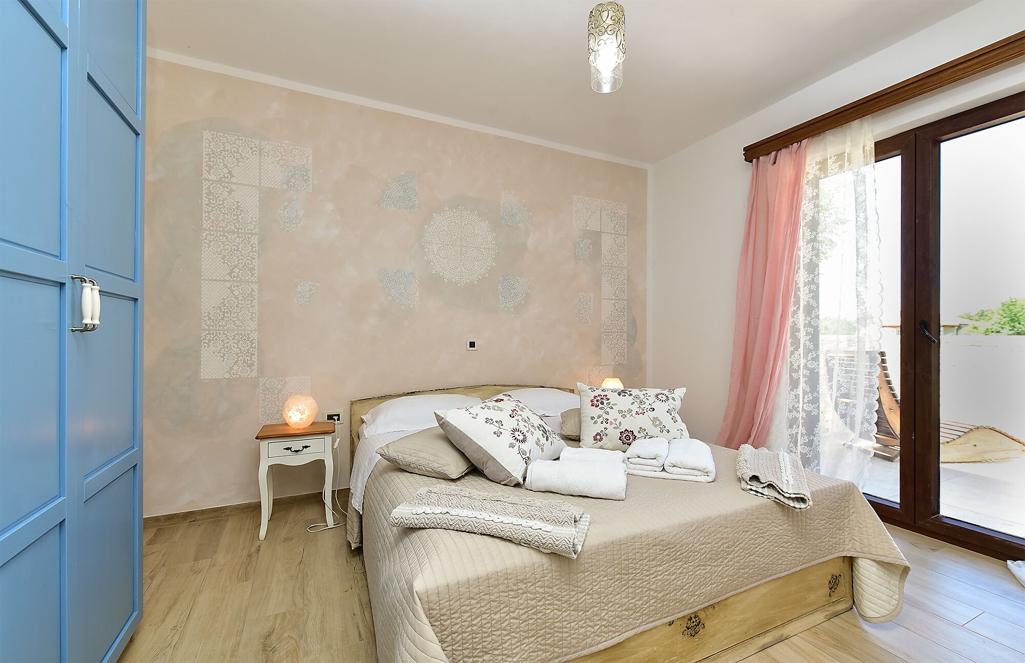 Une chambre à coucher avec un lit, une table de chevet, une lampe et une vue sur l’extérieur.