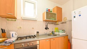 Una cocina con armarios de madera, estufa a gas, lavamanos y refrigerador.