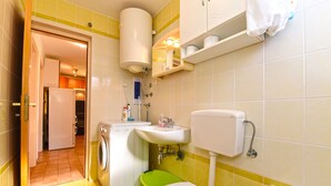 Ein kleines Badezimmer mit Waschmaschine, Toilette, Waschbecken und Badewanne.
