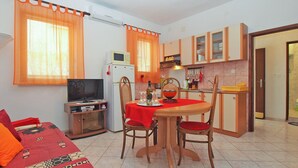 Ein kompakter Wohnraum mit Essbereich, Küchenzeile und Fernseher.