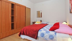 Ein Schlafzimmer mit einem Bett, einem Kleiderschrank, einem Spiegel und einem Nachttisch mit einer Lampe.