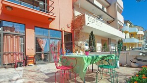 An outdoor seating area with a table and chairs, a potted plant, and a building with balconies and large windows. - Apartment 1571/24205 (Istria - Pula), 1500m from the beach (Pula)