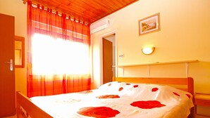 A bedroom with a wooden bed, a window with red curtains, a wall-mounted light, and a door. - Apartment 1576/16148 (Istria - Medulin), 1000m from the beach (Medulin)