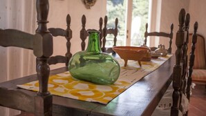 Une table à manger avec une bouteille en verre verte, un bol marron et une nappe à motifs jaunes.