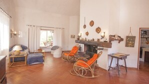 Un salon chaleureux avec une cheminée, des fauteuils en osier et un coin repas.