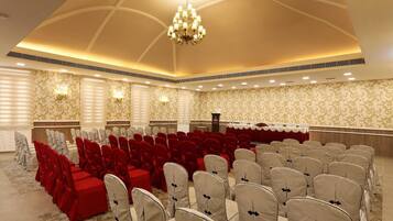 A banquet hall with rows of chairs, a stage, and a chandelier.