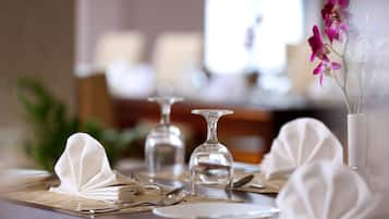 A dining table set with white napkins, cutlery, and a vase with flowers.