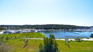 A marina with boats docked, a grassy area, and a hilly landscape in the background. - Apartment 1586/16261 (Istria - Pula), 1000m from the beach (Pula)