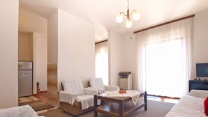 A hotel room with a bed, a sofa, a small table, a chair, a heater, and a TV. - Apartment 1586/16261 (Istria - Pula), 1000m from the beach (Pula)