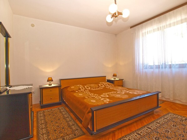 Een slaapkamer met een houten bed, twee nachtkastjes, een spiegel en een kroonluchter.