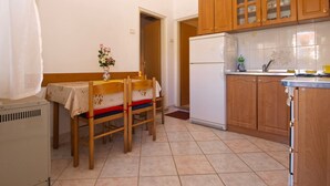 A kitchen with wooden cabinets, a white refrigerator, and a dining table with chairs. - Apartment 1588/16265 (Istria - Pula), 1500m from the beach (Pula)