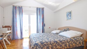 Un dormitorio con cama, una silla, una mesa y cortinas.