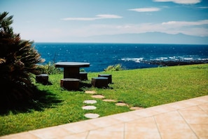 A grassy outdoor area with a stone table and benches, leading to a view of the ocean. - Resort villa miko (Oshima)
