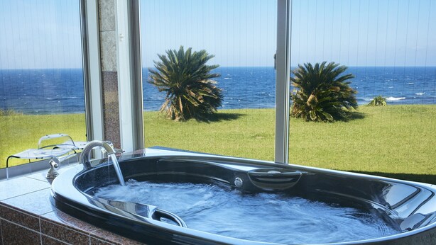 A hot tub with a view of the ocean and palm trees. - Resort villa miko (Oshima)