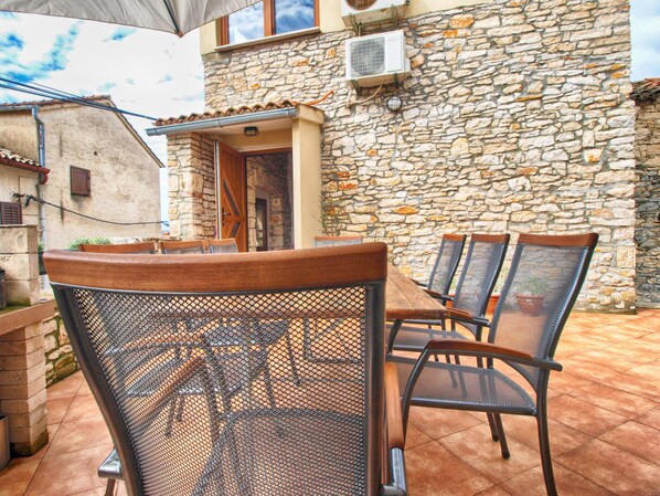 An outdoor patio with a stone wall, a wooden table, and mesh chairs. - House 1599/16347 (Istria - Medulin), 600m from the beach (Medulin)