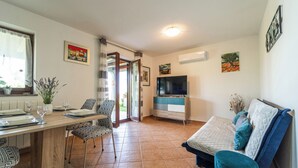Un espacio habitable compacto con zona de comedor, sofá y televisor.