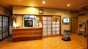 A reception area with a wooden counter, a clock, a television, and a heater.