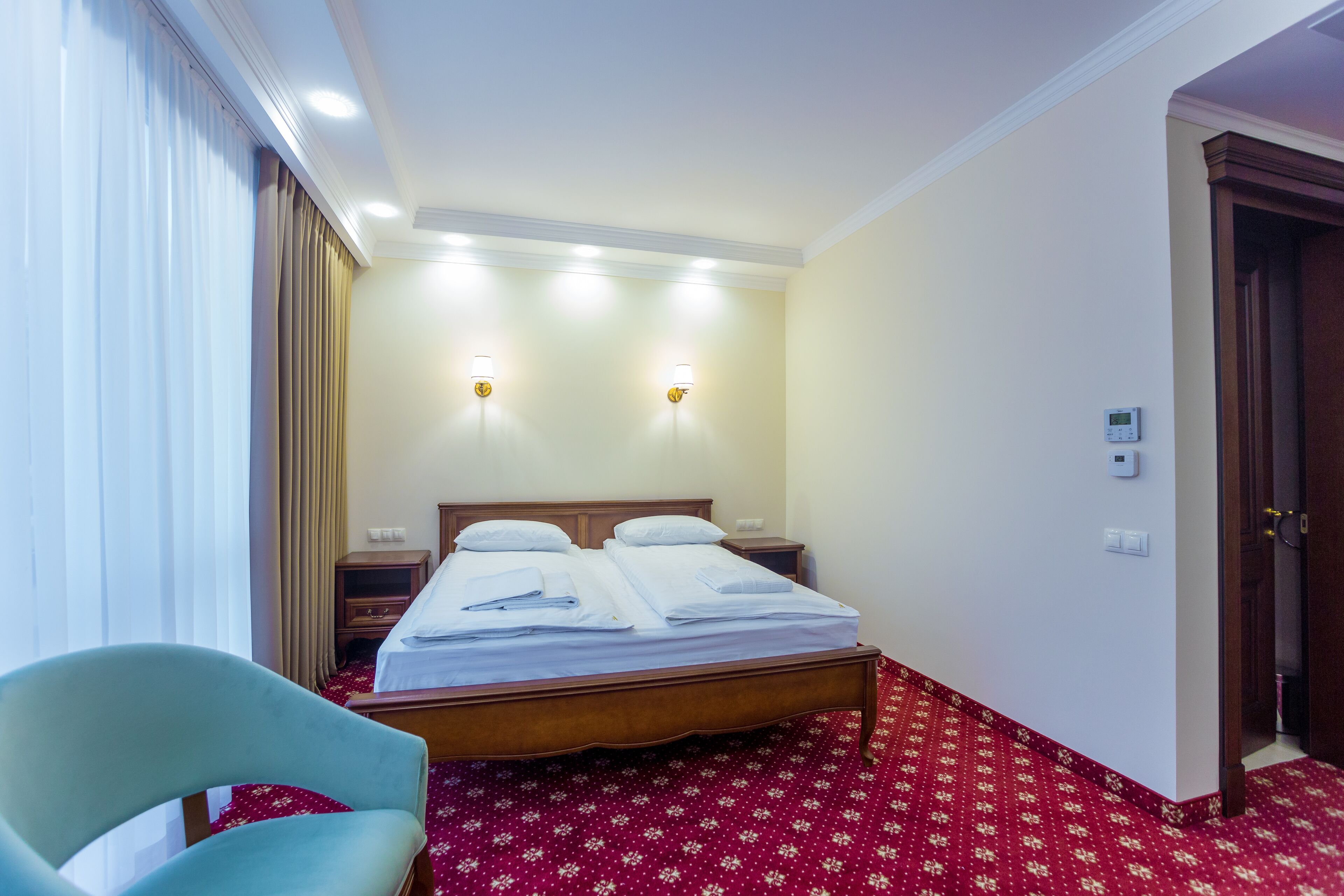 Ein Hotelzimmer mit einem Bett, einem Sessel, einem Nachttisch und einer Tür.