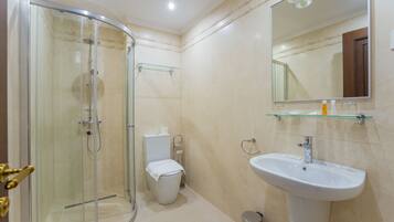 Un baño moderno con cabina de ducha de vidrio, inodoro y lavamanos pedestal.
