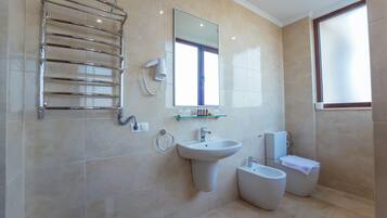 Un baño moderno con cabina de ducha de vidrio, lavabo pedestal, bidé e inodoro.