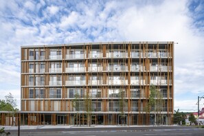 A multi-story building with a modern design, featuring vertical wooden slats on the facade and large windows. - Fenix Furano (Furano)