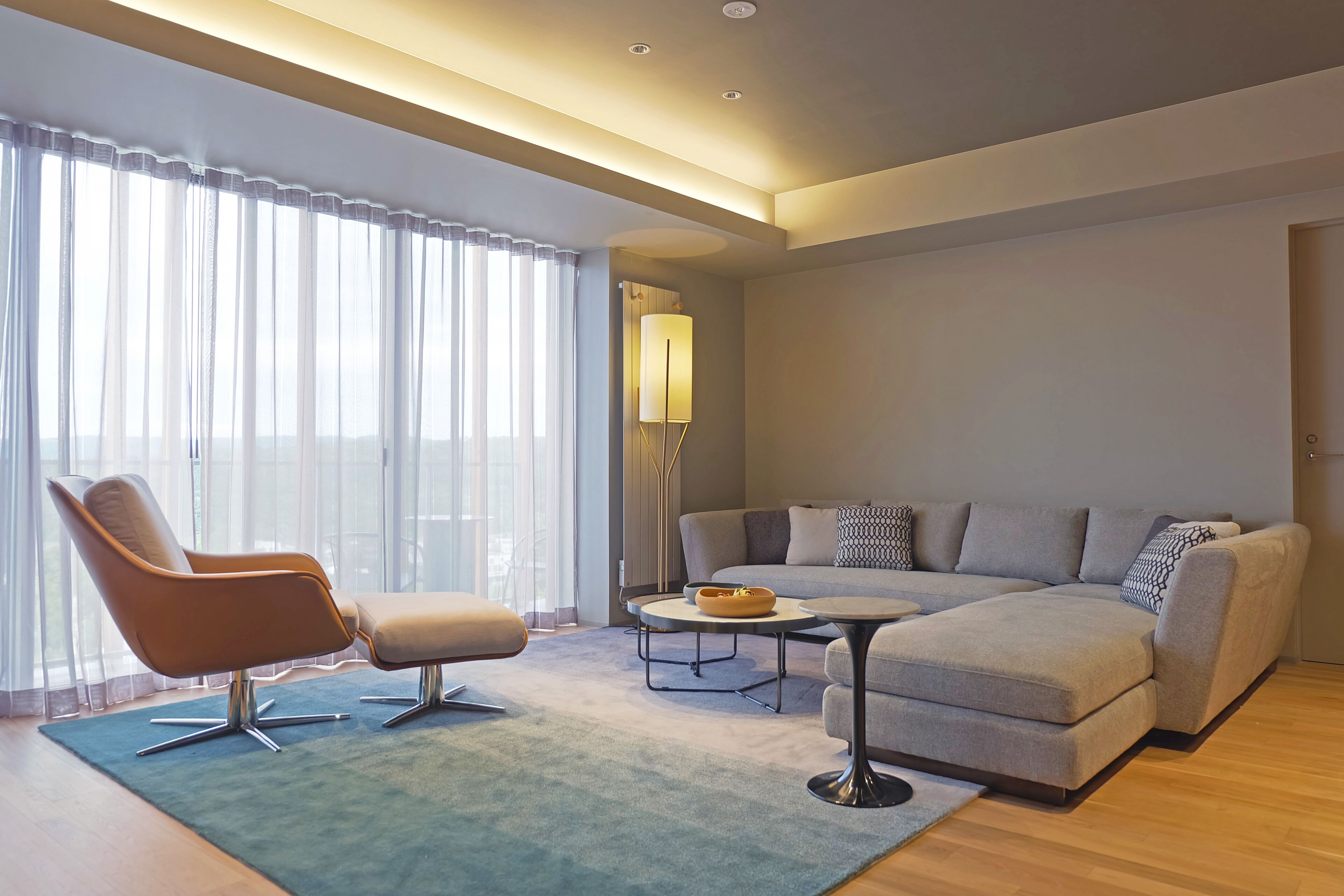 A modern living room with a sofa, armchair, coffee table, and floor lamp.