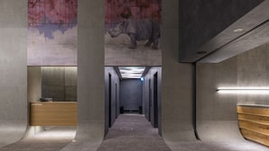 A hallway with a reception desk, a wooden bench, and a large mural of a rhinoceros on the wall. - Fenix Furano (Furano)