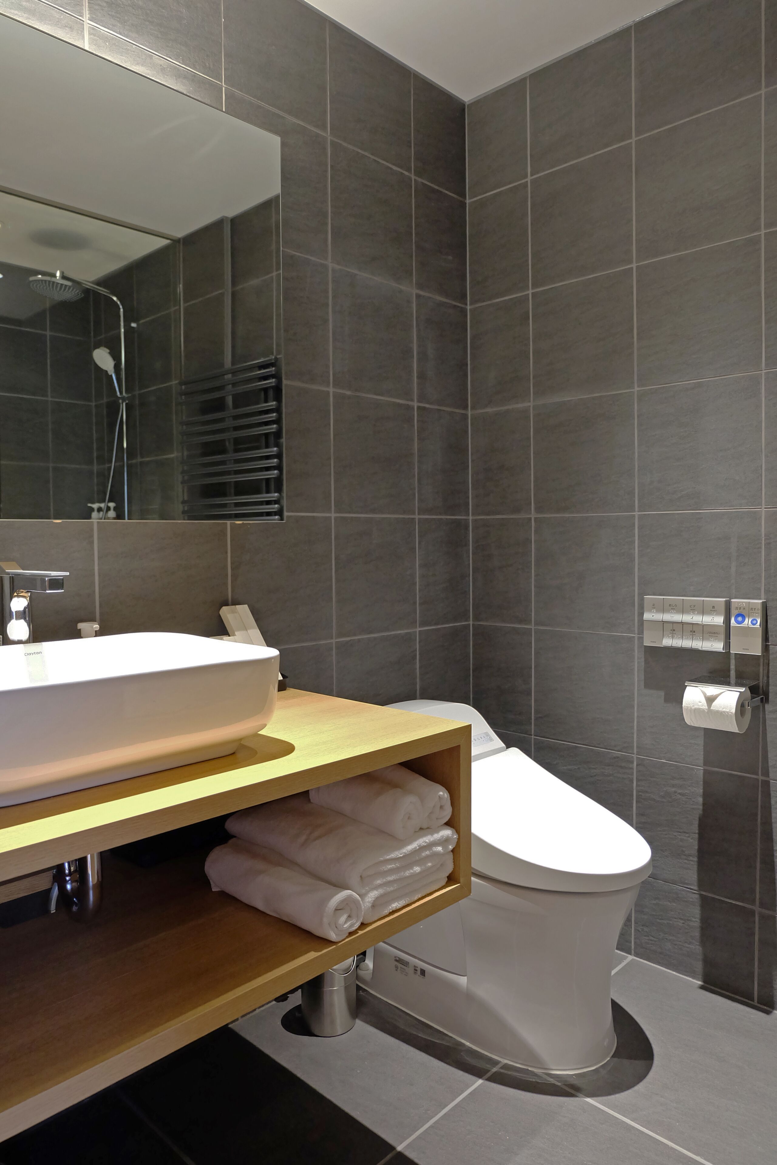 A modern bathroom with a large sink, toilet, and a towel rack.