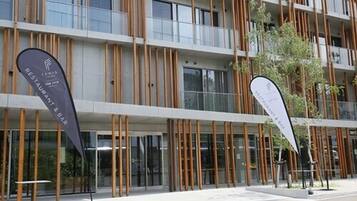 A modern building with vertical wooden slats, large windows, and two flags indicating a restaurant and bar.