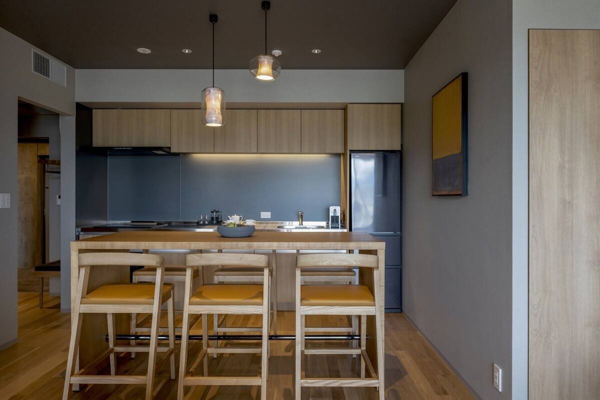 A modern kitchen with wooden cabinets, a central island, and bar stools.