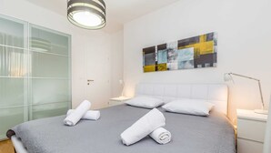A modern hotel room with a large bed, white headboard, and a contemporary abstract painting on the wall. - Holiday house VESNA with pool (Milovčići)