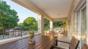 A wooden table with a vase on a balcony with a view of trees and a stone wall. - Holiday house VESNA with pool (Milovčići)