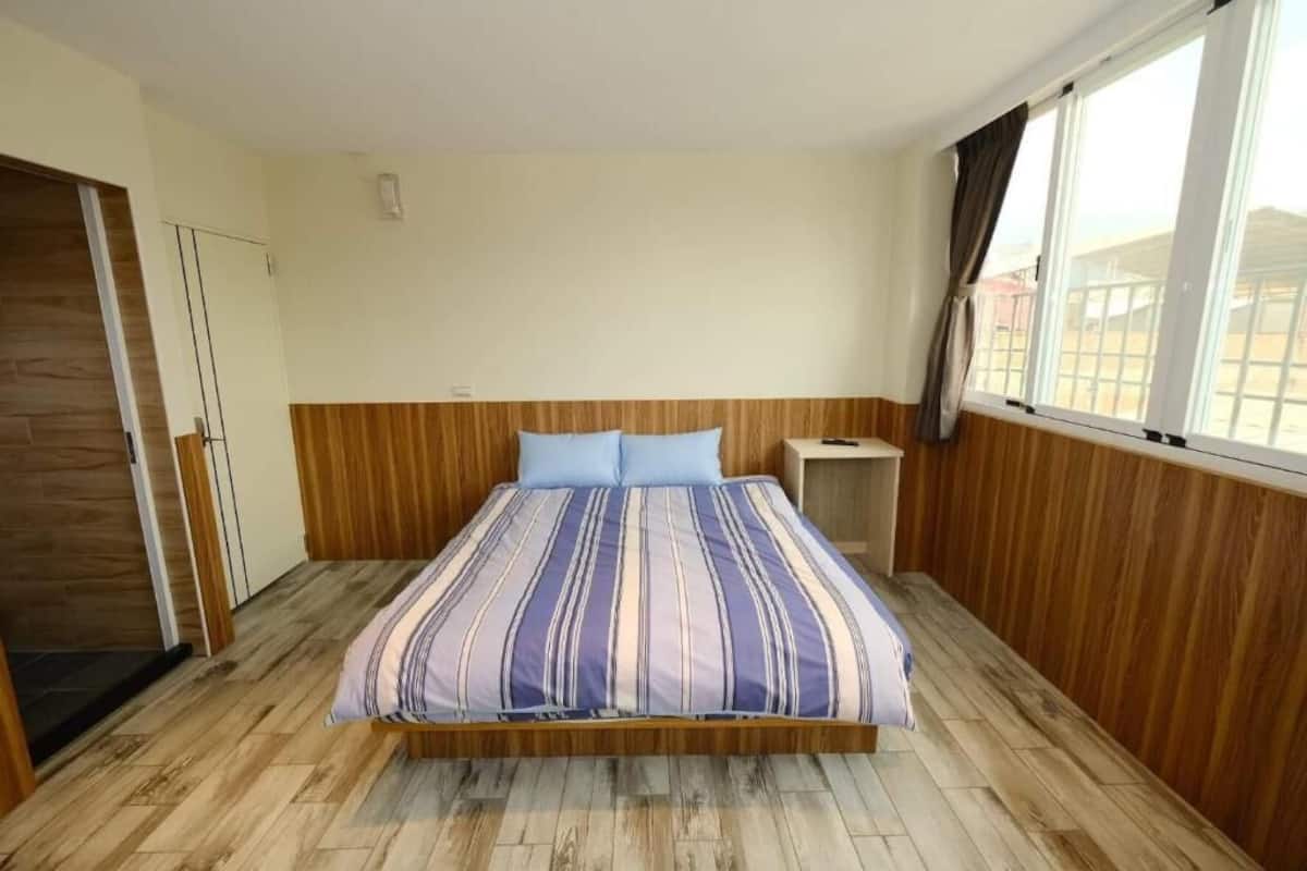 A bedroom with a wooden bed frame, a striped bedspread, and a nightstand.