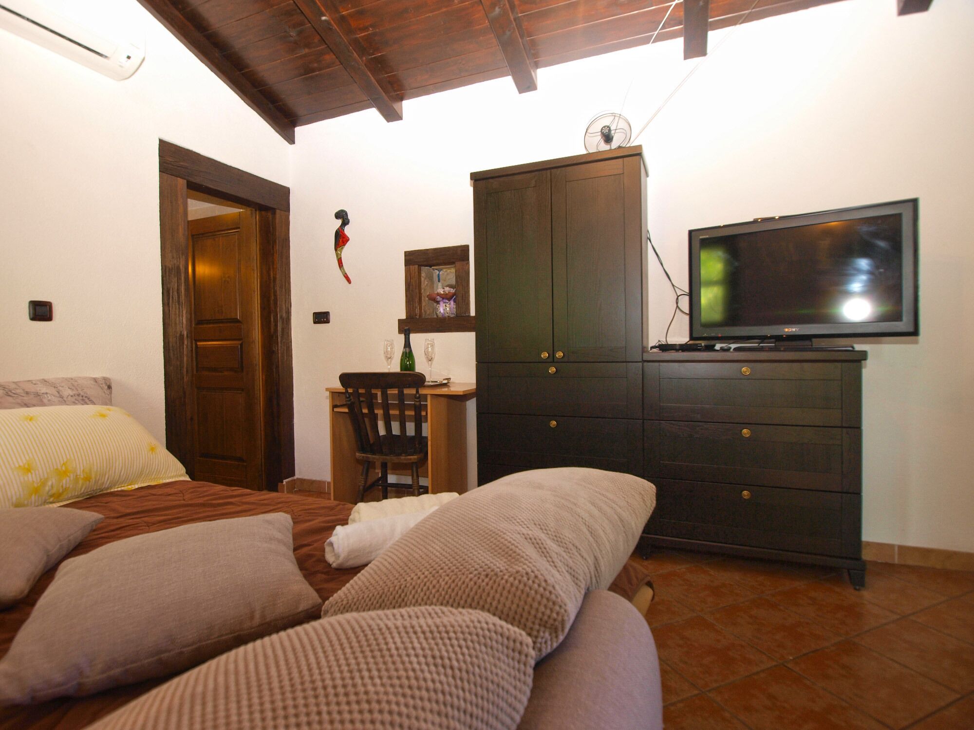 Una camera da letto con un letto, una scrivania in legno, una televisione e un armadio.