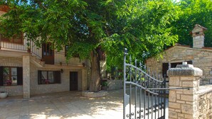 A courtyard with a stone building, a metal gate, and a tree providing shade. - Apartment 1655/17138 (Istria - Matohanci), 9000m from the beach (Matohanci)