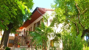 A building with a red roof, a stone staircase, and a garden with various plants and flowers. - Apartment 1655/17138 (Istria - Matohanci), 9000m from the beach (Matohanci)