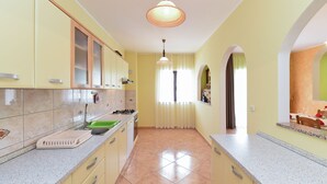 Une cuisine avec des meubles de couleur jaune, un plan de travail en granit, un évier et une fenêtre avec des rideaux.