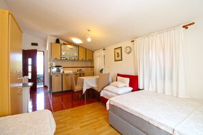 Ein kleines Zimmer mit KĂŒchenzeile, Essbereich und zwei Betten.
