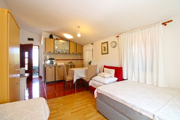 Habitación compacta con kitchenette, comedor y dos camas.