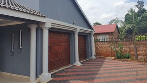 Una casa con fachada gris, dos puertas de garaje y techo de tejas rojas.