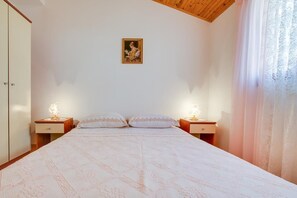 A bedroom with a large bed, two bedside tables with lamps, a wardrobe, and a painting on the wall. - Apartment 1682/17434 (Istria - Pula), 1500m from the beach (Pula)