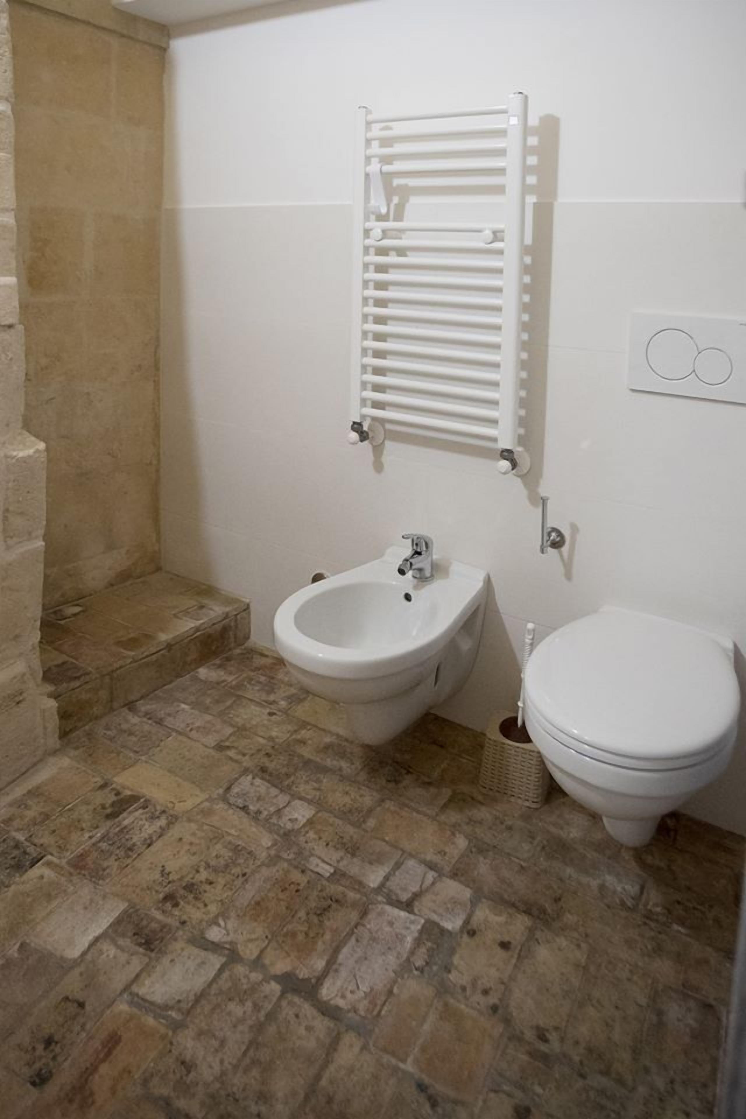Een badkamer met een hygiëneschuimer, toilet en een handdoekhouder.